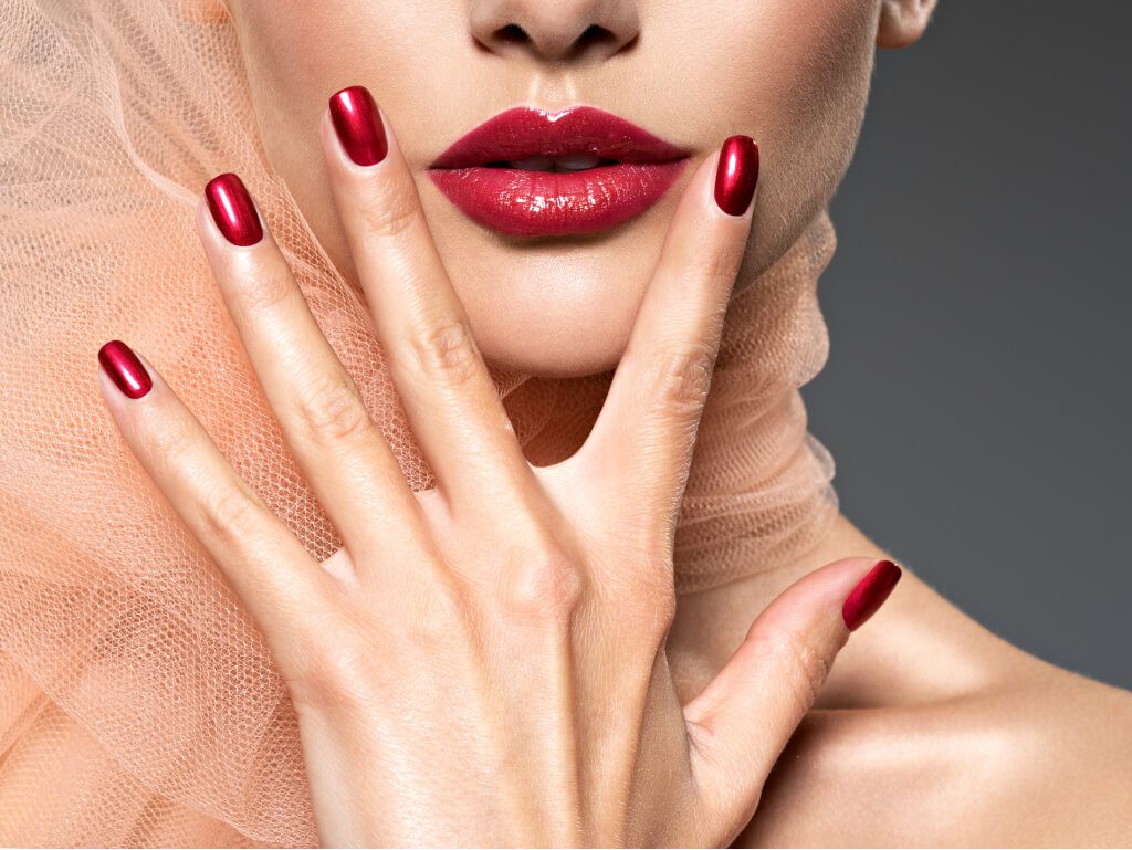 closeup face of a woman with red nails and lips utc